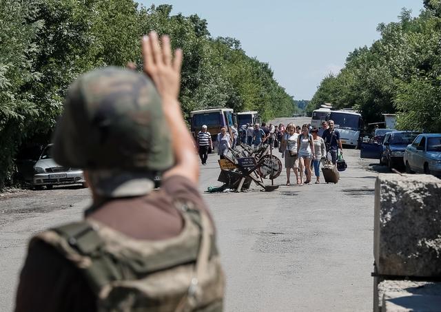 A member of the Ukrainian State Border Guard Service gives a sign to people to stop as they approach a checkpoint at the contact line between pro-Russian rebels and Ukrainian troops in Mayorsk, Ukraine July 3, 2019. REUTERS/Gleb Garanich