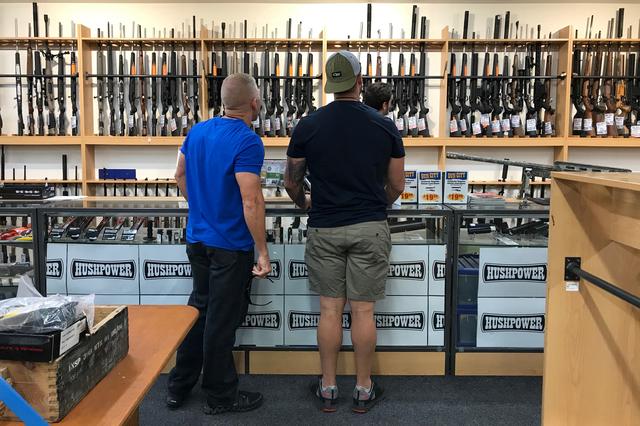 FILE PHOTO: People look at firearms and accessories on display at Gun City gunshop in Christchurch, New Zealand, March 19, 2019. REUTERS/Jorge Silva/File Photo