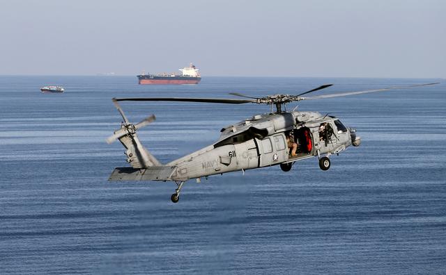 FILE PHOTO: An MH-60S helicopter hovers in the air with an oil tanker in the background as the USS John C. Stennis makes its way to the Gulf through the Strait of Hormuz, December 21, 2018. REUTERS/Hamad I Mohammed/File Photo