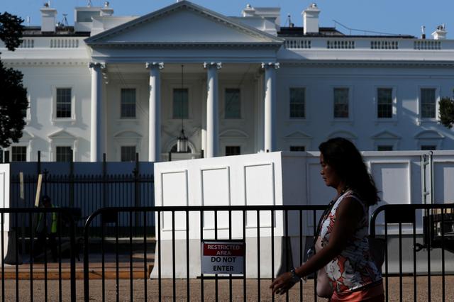 FILE PHOTO: Pedestrian walks next to the wall that is being built at the White House to facilitate the workers task modernizing the compound’s security fence along Pennsylvania Avenue in Washington, U.S. July 22, 2019.  REUTERS/Jonathan Ernst