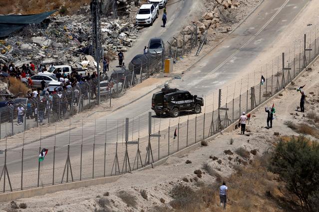 Palestinian demonstrators protest against the Israeli demolitions of Palestinian homes as an Israeli police vehicle is seen, in the village of Sur Baher which sits on either side of the Israeli barrier in East Jerusalem and the Israeli-occupied West Bank July 26, 2019. REUTERS/Mussa Qawasma