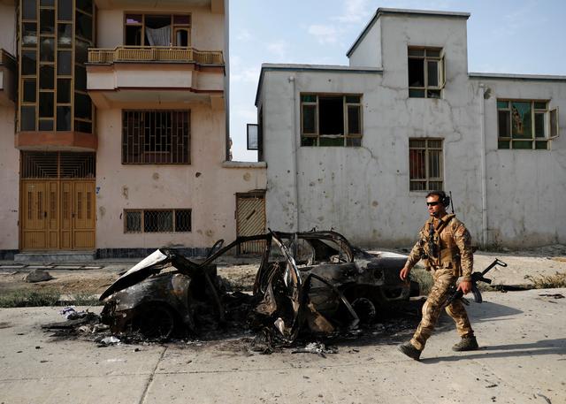 An Afghan security force walks past a burnt vehicle after Sunday’s attack at the site in Kabul, Afghanistan July 29, 2019. REUTERS/Mohammad Ismail
