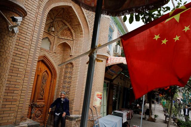 An elderly man is seen behind a Chinese national flag in the Old City in Kashgar in Xinjiang Uighur Autonomous Region, China September 6, 2018.  REUTERS/Thomas Peter