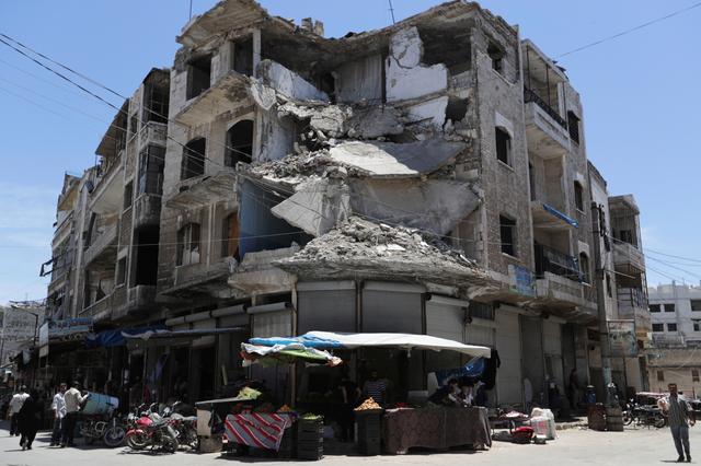 People walk past a damaged building in the city of Idlib, Syria May 25, 2019. REUTERS/Khalil Ashawi