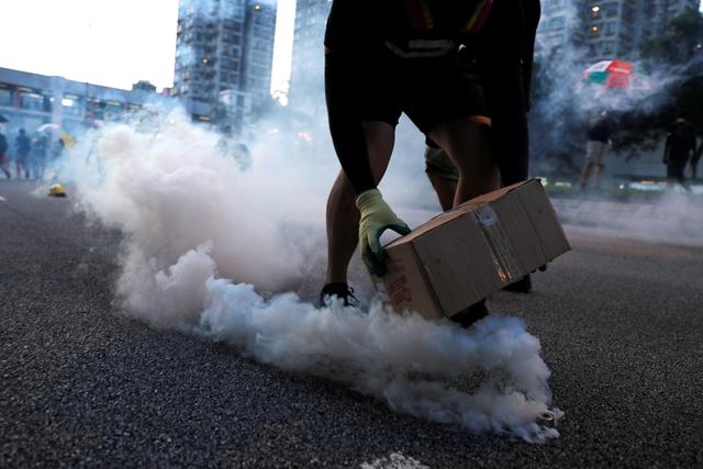 A protester covers a tear gas canister fired by the police during a demonstration in support of the city-wide strike and to call for democratic reforms at Tai Po residential area in Hong Kong, China, August 5, 2019. REUTERS/Tyrone Siu