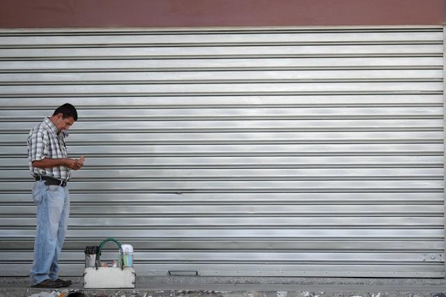 A street seller counts money in front of a closed local shop in Valencia, Venezuela, Venezuela, April 8, 2019.  REUTERS/Ueslei Marcelino