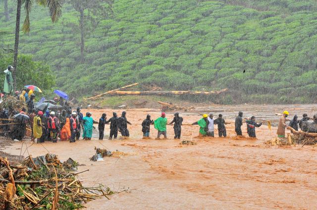 Rescuers help people to cross a flooded area after a landslide caused by torrential monsoon rains in Meppadi in Wayanad district in the southern Indian state of Kerala, India, August 9, 2019. REUTERS/Stringer