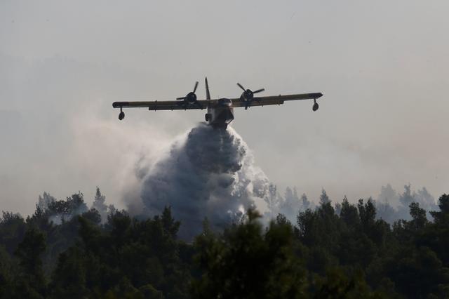 A firefighting plane makes a water drop as a wildfire burns near the village of Stavros on the island of Evia, Greece, August 14, 2019. REUTERS/Costas Baltas