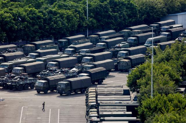 Servicemen walk past military vehicles in the parking area of the Shenzhen Bay Sports Center in Shenzhen across the bay from Hong Kong, China August 16, 2019.  REUTERS/Thomas Peter