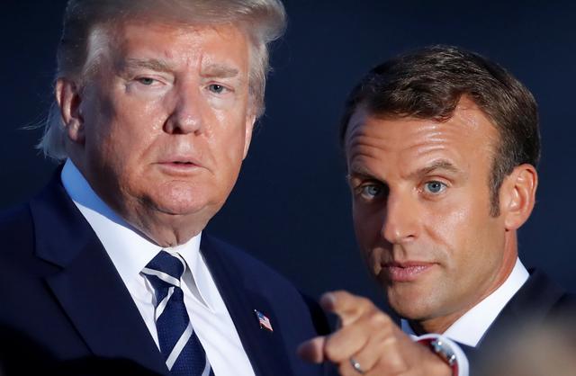 French President Emmanuel Macron points next to U.S. President Donald Trump during the family photo session with invited guests at the G7 summit in Biarritz, France August 25, 2019. REUTERS/Christian Hartmann/Pool