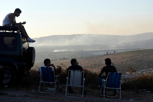 Israelis sit and watch smoke on the Lebanese side of the Israel-Lebanon border, as seen from its Israeli side September 1, 2019. REUTERS/Rami Shlush 
