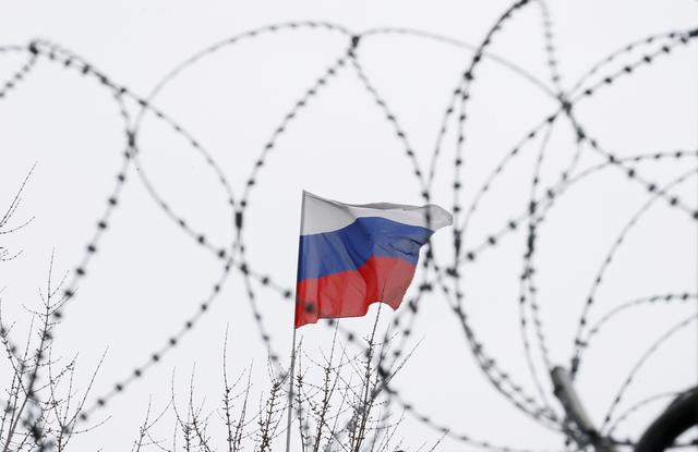 The Russian flag is seen through barbed wire as it flies on the roof of the Russian embassy in Kiev, Ukraine March 26, 2018. REUTERS/Gleb Garanich  