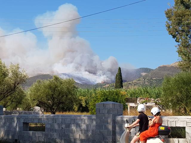 People look at the smoke rising from the side of a hill due to a wildfire on the island of Zakynthos, Greece September 15, 2019. in this still image obtained from social media. ANJA FRUGTE-POSTEMA/via REUTERS 