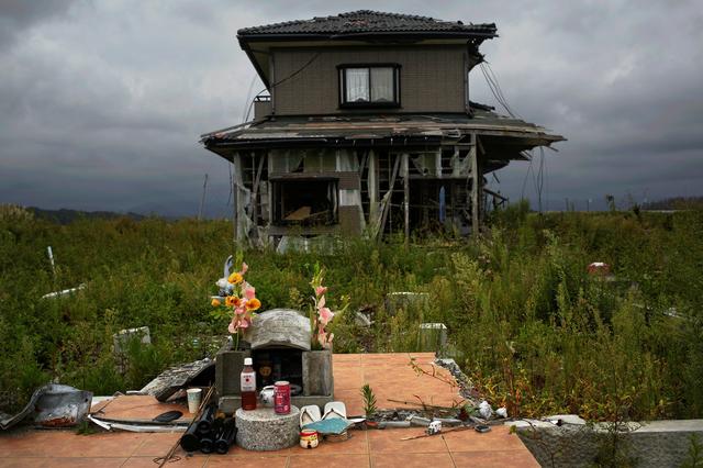 FILE PHOTO: A small monument to victims is seen in front of an abandoned house at the tsunami destroyed coastal area of the evacuated town of Namie in Fukushima prefecture, some 6 km (4 miles) from the crippled Daiichi power plant, September 22, 2013. REUTERS/Damir Sagolj/File Photo