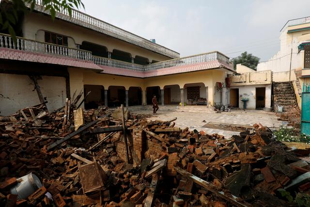 A boy walks on the floor of a newly build house as the rubble of an old house that fallen during an earthquake is seen in Jatlan, Mirpur, Pakistan September 25, 2019.  REUTERS/Akhtar Soomro