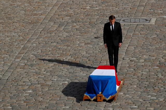 French President Emmanuel Macron stands in front of the flag-draped coffin of late French President Jacques Chirac during a military funeral honors ceremony at the Hotel des Invalides during a national day of mourning in Paris, France, September 30, 2019. REUTERS/Gonzalo Fuentes