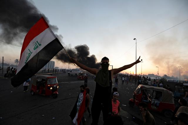 A demonstrator holds an Iraqi flag at a protest after the lifting of the curfew, following four days of nationwide anti-government protests that turned violent, in Baghdad, Iraq October 5, 2019. REUTERS/Thaier Al-Sudani