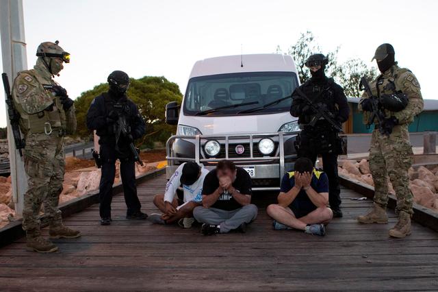 Police officers stand around suspects arrested during an operation that, according to police, resulted in the seizure of 1.2 tonnes of methamphetamine in Geraldton, Australia, December 21, 2017. Picture taken December 21, 2017.   Australian Federal Police/Handout via REUTERS  