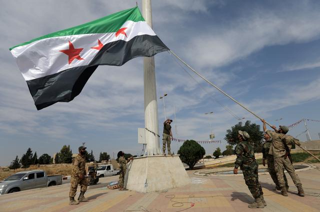 Turkey-backed Syrian rebel fighters raise the Syrian opposition flag at the border town of Tel Abyad, Syria, October 14, 2019. REUTERS/Khalil Ashawi