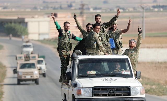 Turkey-backed Syrian rebel fighters gesture as they ride on a vehicle near the border town of Tal Abyad, Syria, October 22, 2019. REUTERS/Khalil Ashawi     TP
