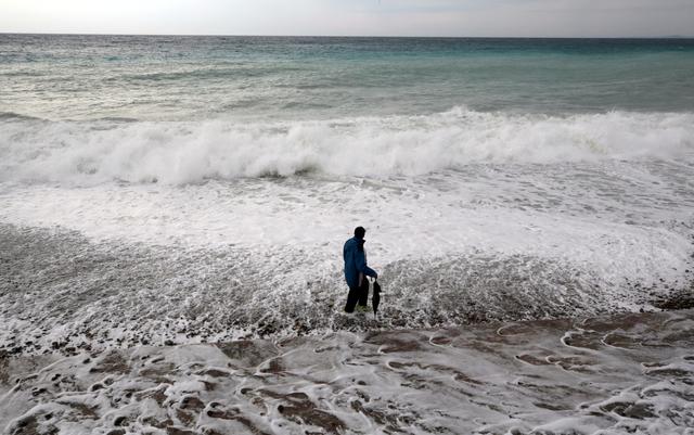 FILE PHOTO: A man walks on the beach in Nice as storms and heavy rain lashed through southern France, October 23, 2019.  REUTERS/Eric Gaillard/File Photo