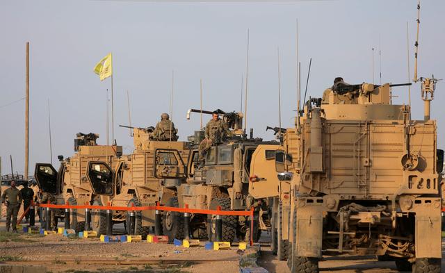 FILE PHOTO: American soldiers stand near military trucks, at al-Omar oil field in Deir Al Zor, Syria March 23, 2019. REUTERS/Rodi Said/File Photo