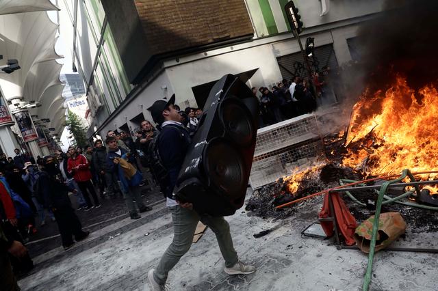 FILE PHOTO: A man prepares to throw a speaker into a burning barricade while vandalizing a shop during a protest against Chile's state economic model in Concepcion, Chile October 28, 2019. REUTERS/Juan Gonzalez/File Photo
