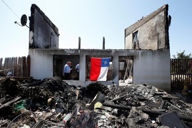 A Chilean flag hangs off the remains of a house, after it was destroyed by fire, following the spread of wildfires in Valparaiso, Chile  December 26, 2019. REUTERS/Rodrigo Garrido