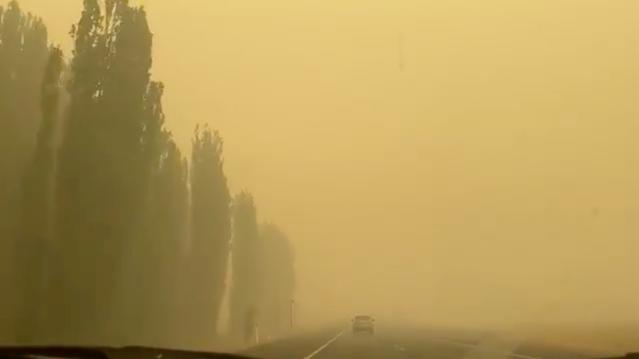 A vehicle is engulfed in yellowish smoke as it travels along a highway during bushfires near Cooma, New South Wales, Australia January 1, 2020 in this picture obtained from social media. Mandatory credit JODIE BRADBY CANBERRA AUSTRALIA/via REUTERS 