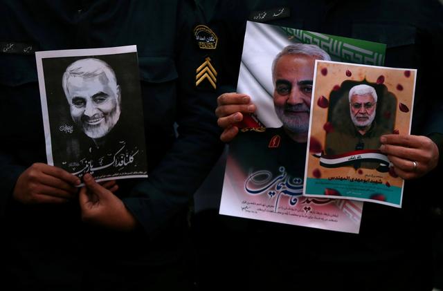  Iranian guards hold a picture of the late Iranian Major-General Qassem Soleimani, during a protest against the killing of Soleimani, head of the elite Quds Force, and Iraqi militia commander Abu Mahdi al-Muhandis, who were killed in an air strike at Baghdad airport, in front of United Nation office in Tehran, Iran January 3, 2020. WANA (West Asia News Agency)/Nazanin Tabatabaee via REUTERS 