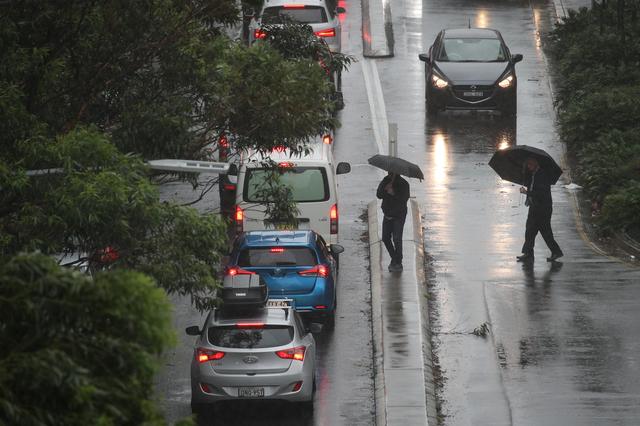 Pedestrians brave strong wind and rain in Sydney, New South Wales, Australia, February 9, 2020.  REUTERS/Loren Elliott
