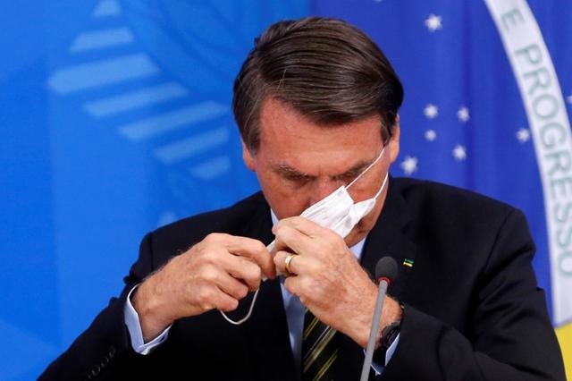 Brazil's President Jair Bolsonaro adjusts his protective face mask during a press statement to announce federal judiciary measures to curb the spread of the coronavirus disease (COVID-19) in Brasilia, Brazil March 18, 2020. REUTERS/Adriano Machado