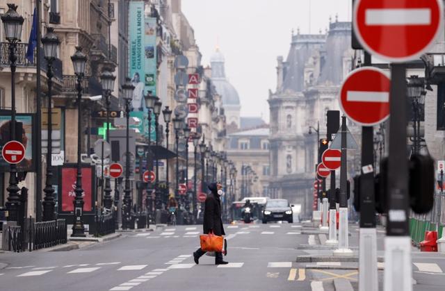 FILE PHOTO: A man wearing a protective face mask crosses the deserted Rue de Rivoli in Paris as a lockdown is imposed to slow the rate of the coronavirus disease (COVID-19) in France, March 18, 2020.  REUTERS/Christian Hartmann     
