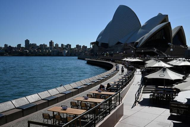 FILE PHOTO: Tables at an open restaurant are seen mostly deserted on a quiet morning at the waterfront of the Sydney Opera House, where scheduled public performances have been cancelled due to the coronavirus disease (COVID-19), in Sydney, Australia, March 18, 2020.  REUTERS/Loren Elliott