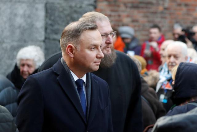 FILE PHOTO: Poland's President Andrzej Duda, seen in front of Director of the Auschwitz-Birkenau State Museum Piotr Cywinski, attends a wreath-laying ceremony at the death wall at the former Nazi German concentration and extermination camp Auschwitz in Oswiecim, Poland, January 27, 2020. REUTERS/Aleksandra Szmigiel/File Photo
