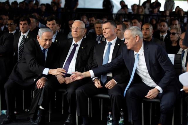FILE PHOTO: Head of Israel's Blue and White Party Benny Gantz and Israeli Prime Minister Benjamin Netanyahu shake hands as they attend a memorial ceremony in Jerusalem , November 10, 2019. Heidi Levine/Pool via REUTERS