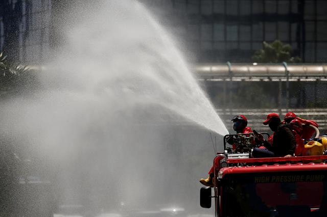Firefighters spray disinfectant using high pressure pump truck to prevent the spread of coronavirus disease (COVID-19), on the main road in Jakarta, Indonesia, March 31, 2020. REUTERS/Willy Kurniawan