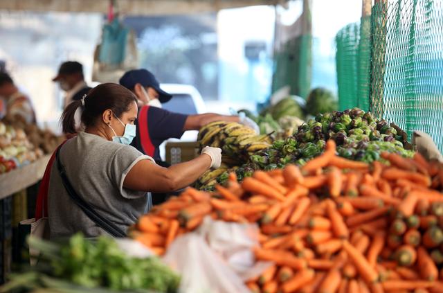 A woman wearing a protective mask picks vegetables in a street market during the nationwide quarantine in response to the spread of coronavirus disease (COVID-19) in Caracas, Venezuela March 31, 2020. REUTERS/Fausto Torrealba NO RESALES. NO ARCHIVE.