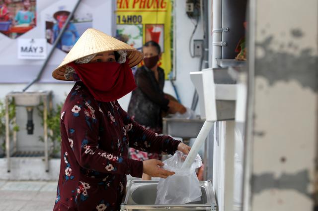 A woman fills a plastic bag with rice from a 24/7 automatic rice dispensing machine 'Rice ATM' during the outbreak of the coronavirus disease (COVID-19), in Ho Chi Minh, Vietnam, April 11, 2020. REUTERS/Yen Duong