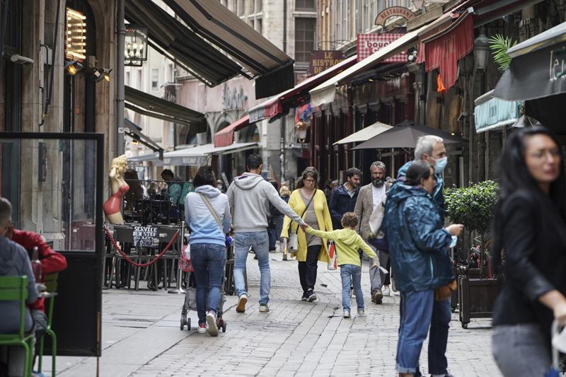 People walk by restaurants in Lyon, central France, Tuesday, July 13, 2021. Nearly 1 million people in France made vaccine appointments in a single day, as the president cranked up pressure on everyone to get vaccinated to save summer vacation and the French economy. (AP Photo/Laurent Cipriani)