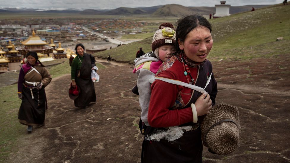 A Tibetan woman carrying a baby on her back (Credit: Getty Images)